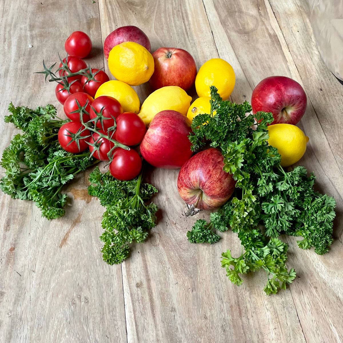 Assortiment de tomates, pommes, citrons et persil frais sur une planche en bois rustique