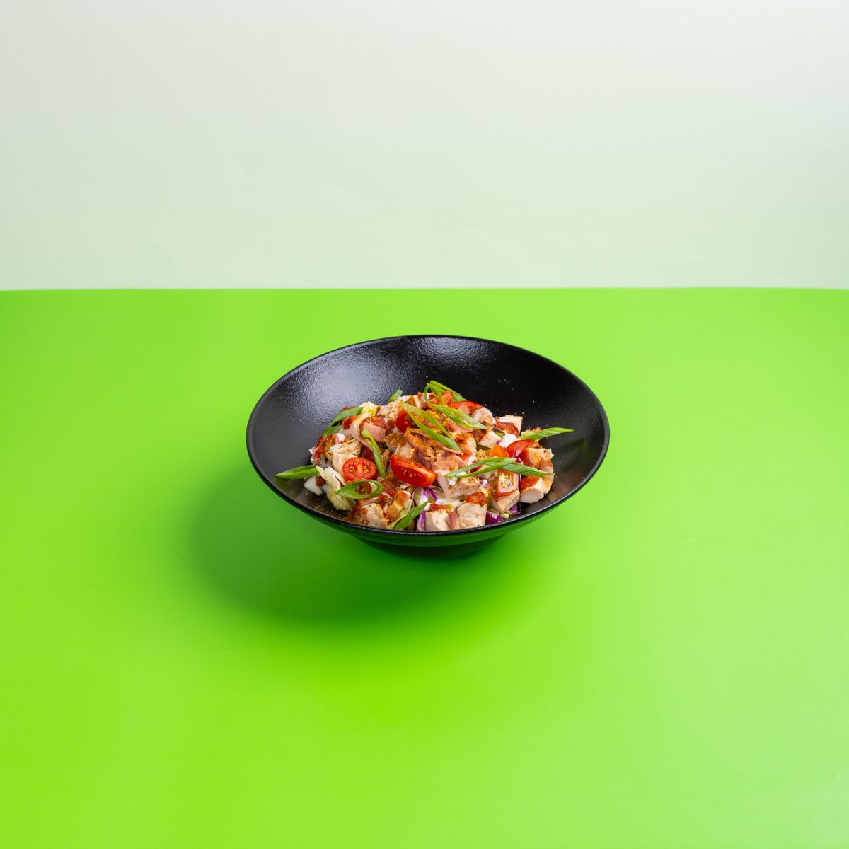 Salade fraîche aux légumes servie dans un bol noir, idéale en plat à emporter