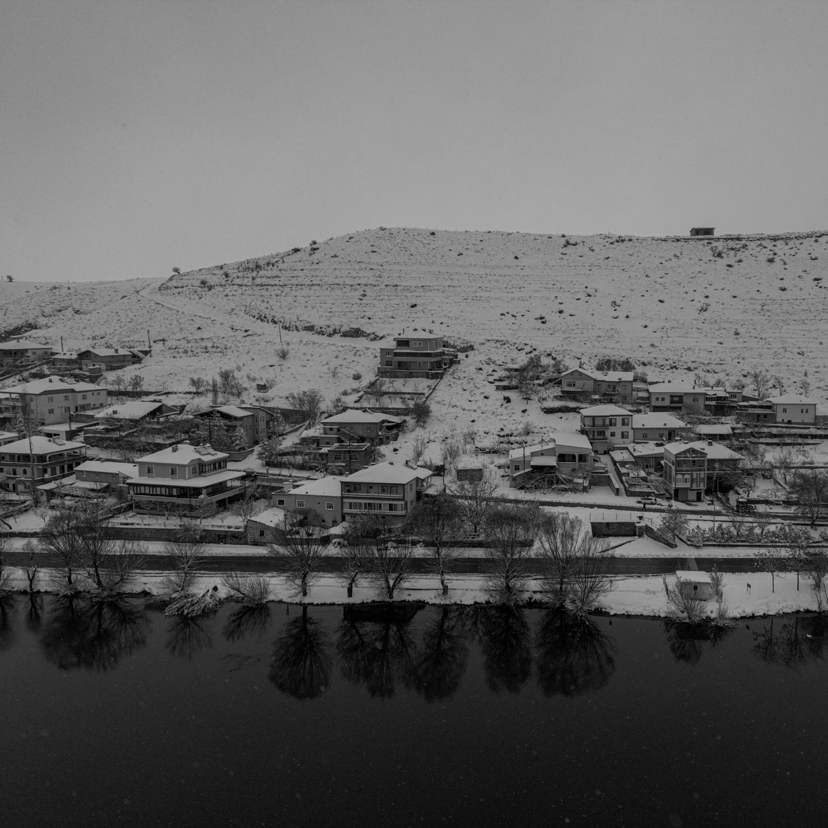 Village de montagne enneigé au bord d'une rivière, ambiance hivernale paisible du Haut-Doubs