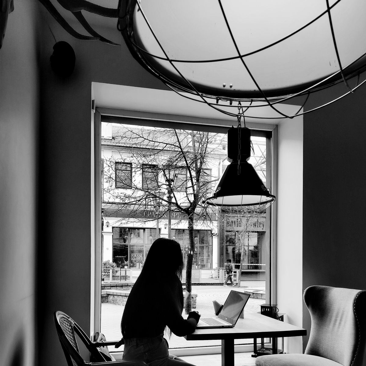 Femme passant commande sur un ordinateur portable, installée dans un café confortable