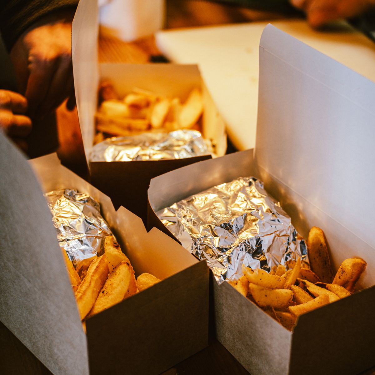 Plats chauds à emporter avec frites emballés dans des boîtes en carton, prêts au retrait