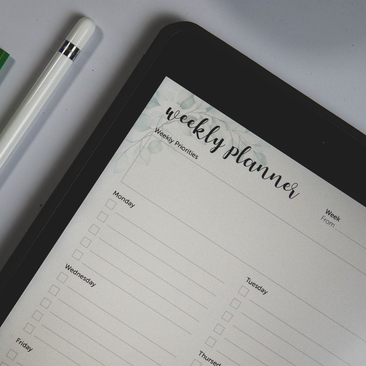 Tablette numérique affichant un organiseur hebdomadaire avec un stylo posé pour planifier une commande