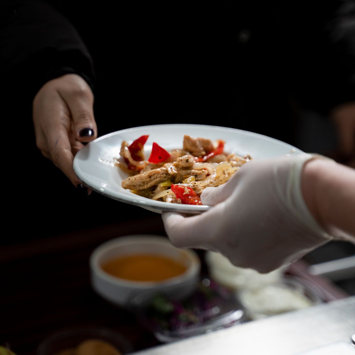 Mains échangeant un plat savoureux servi dans une assiette blanche soignée