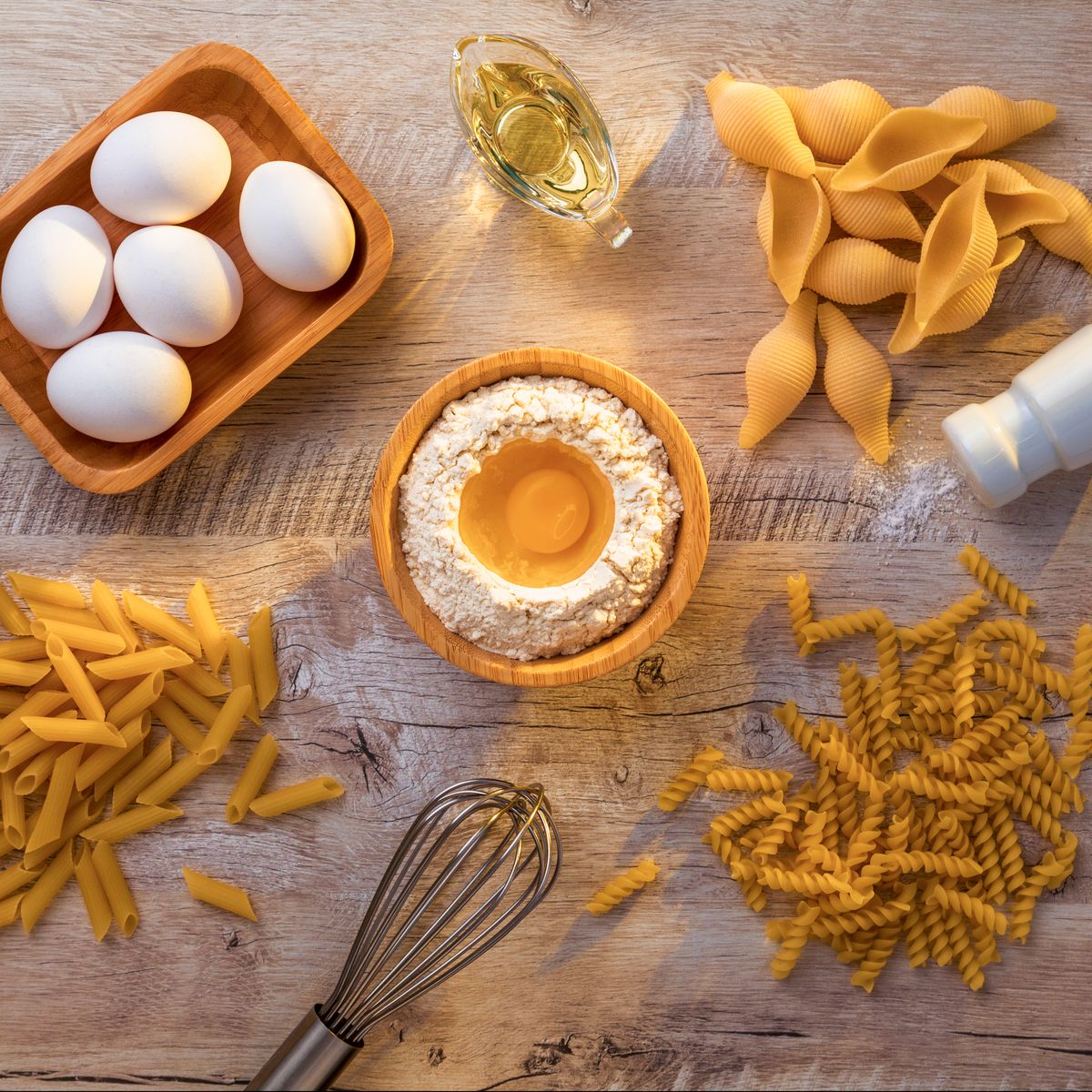 Œufs, farine et huile d'olive disposés pour préparer des pâtes maison, sources d'allergènes