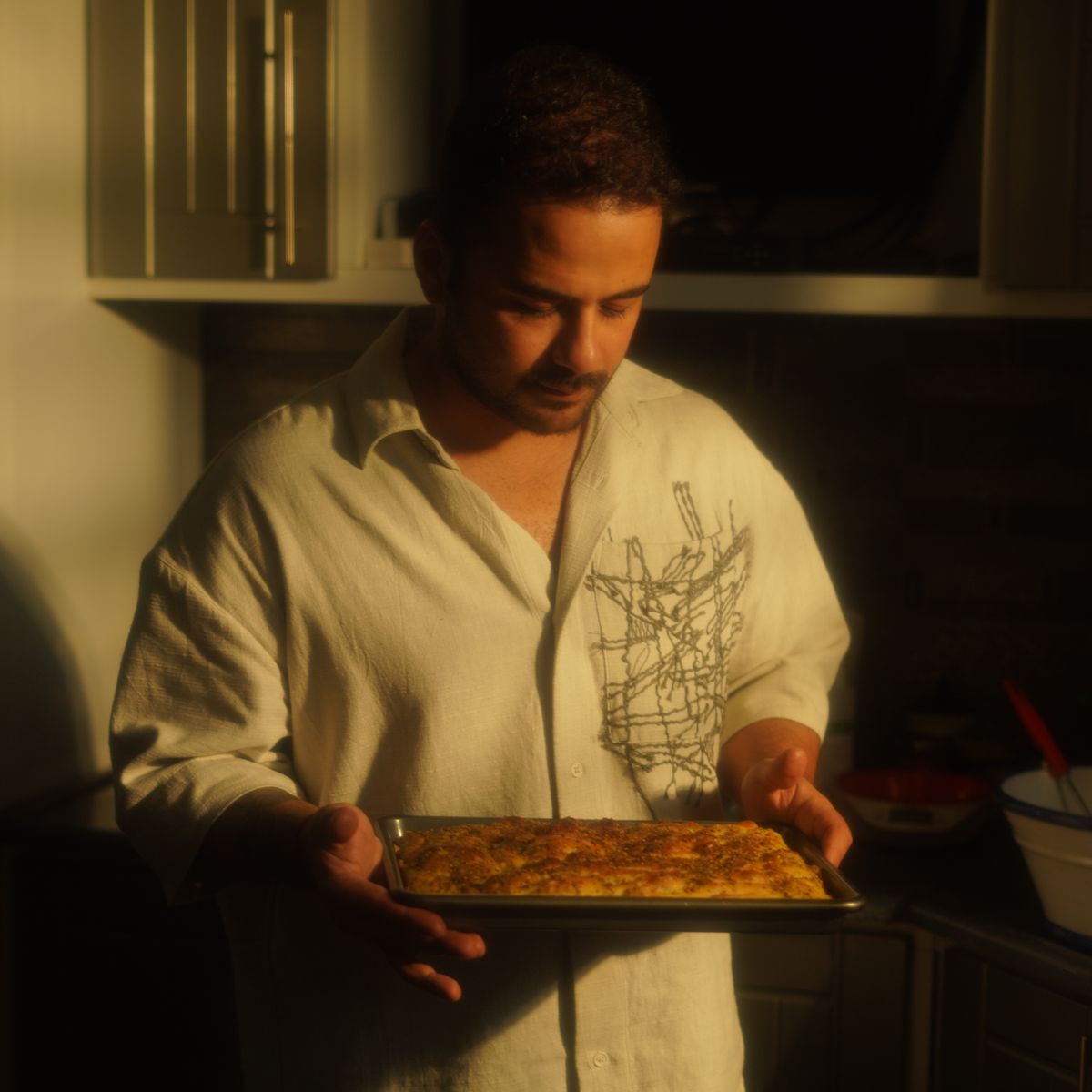 Chef traiteur tenant un pain fraîchement cuit dans une cuisine artisanale chaleureusement éclairée